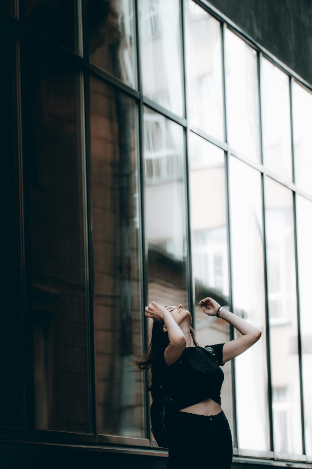 woman in black sleeveless dress standing beside glass window