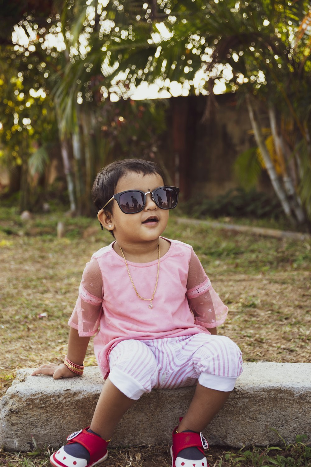 girl in pink shirt and white pants sitting on ground