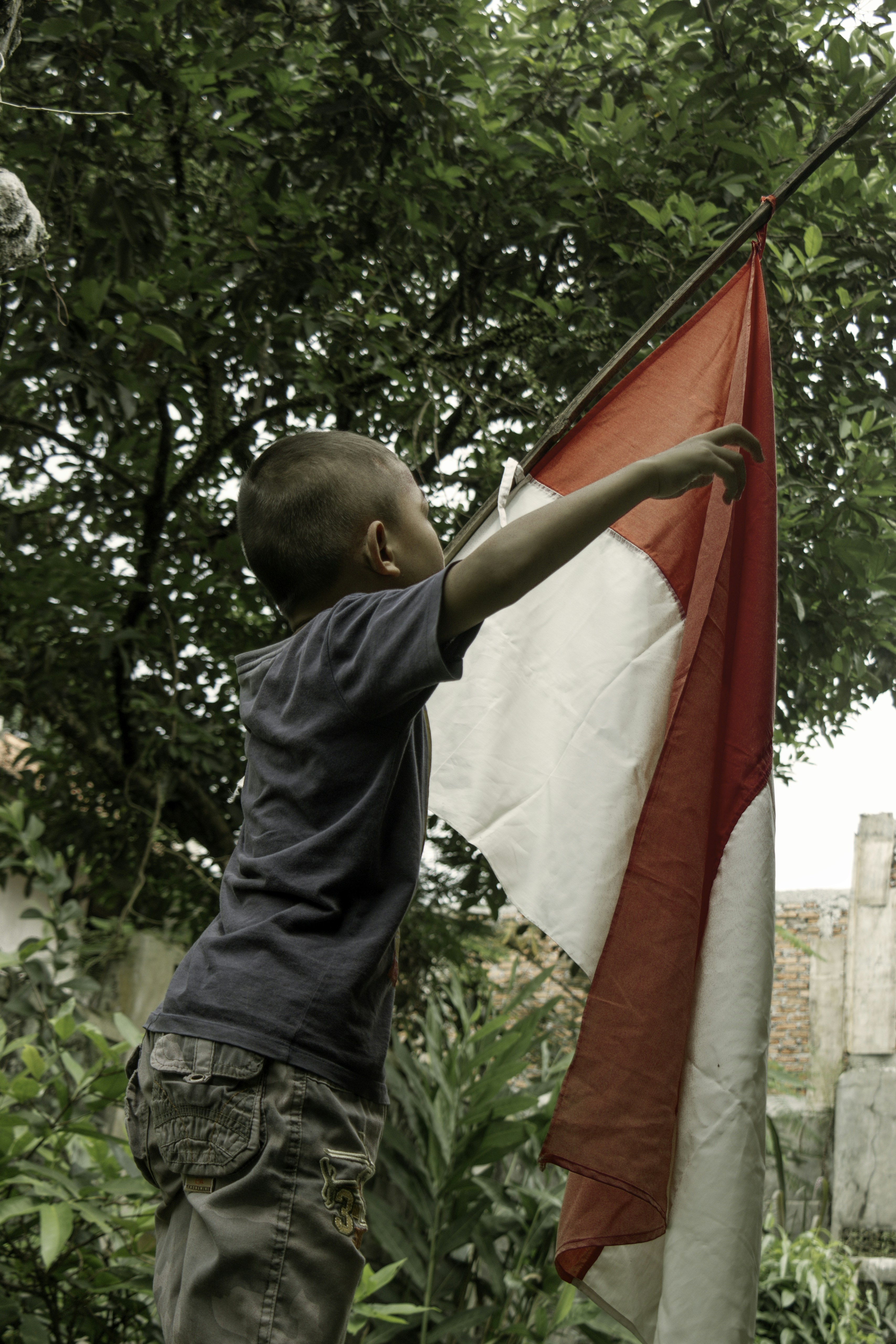 Anak laki-laki berbaju hitam memegang bendera merah dan putih