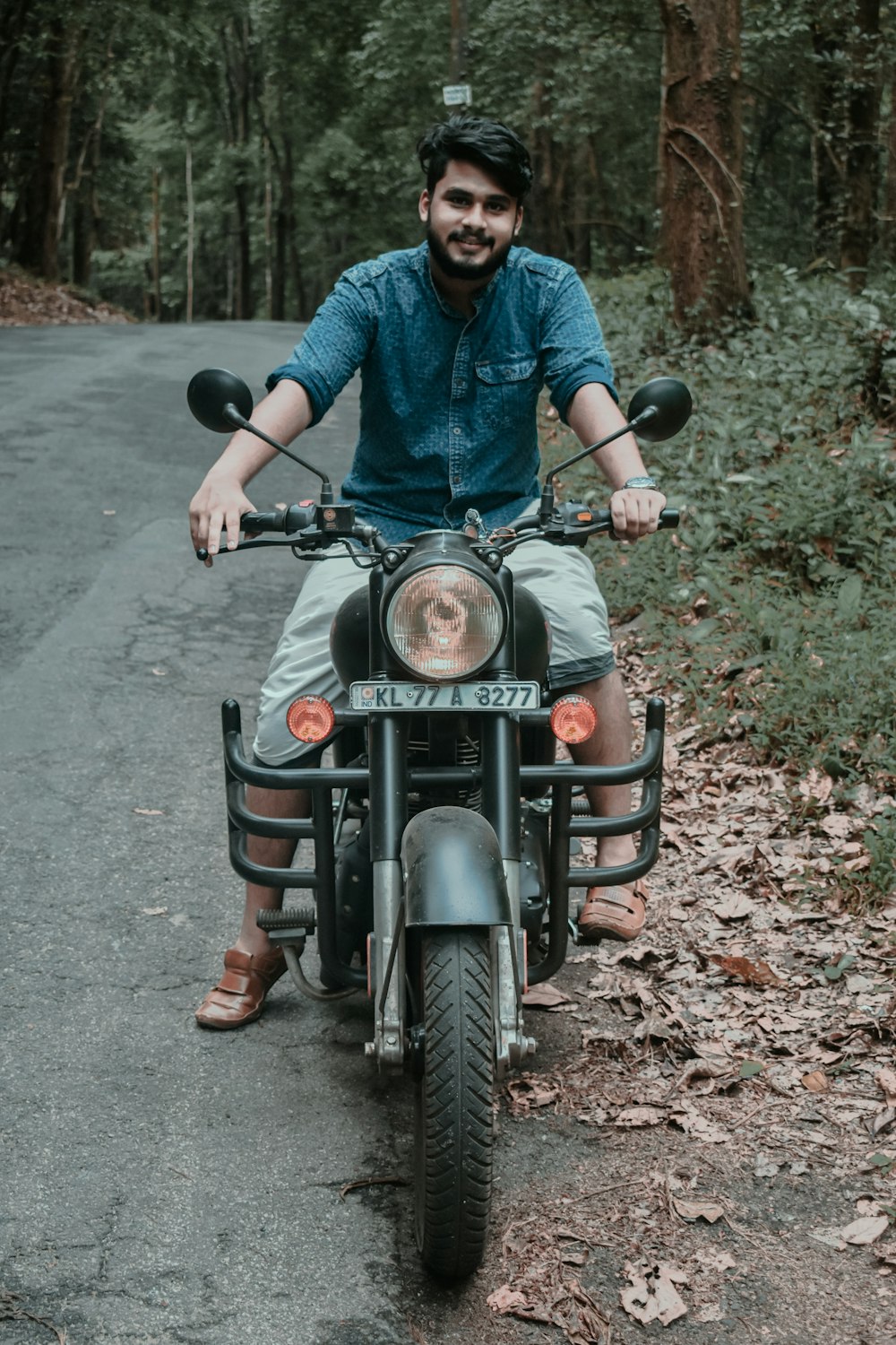 Mann im blauen Hemd fährt schwarzes Motorrad