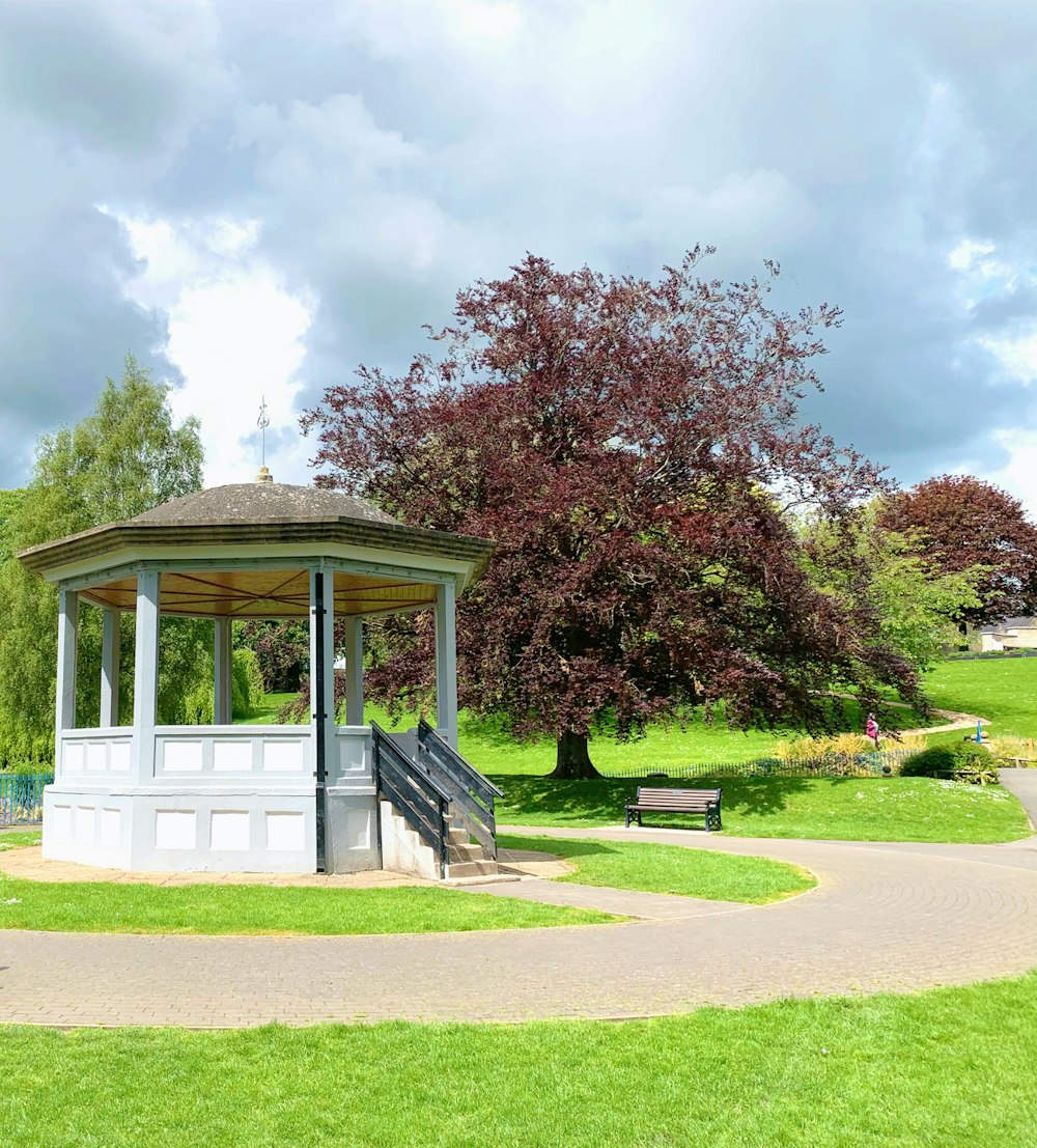 white and brown wooden gazebo near green grass field during daytime