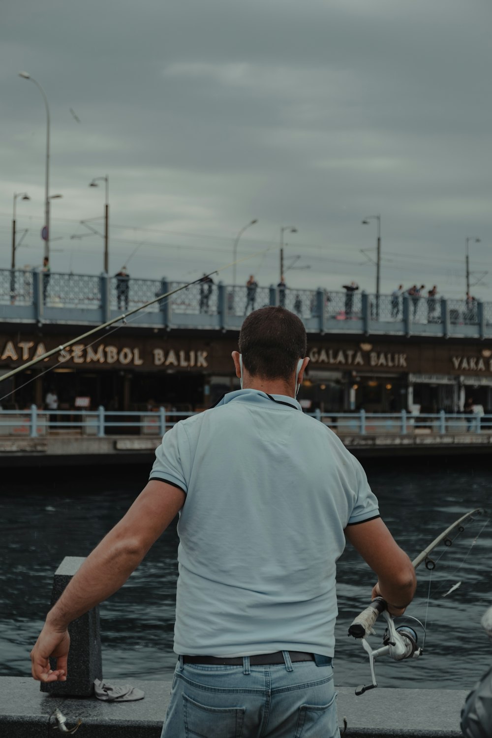 man in white t-shirt standing on dock during daytime