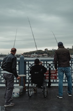 Volunteers assisting individuals with disabilities at a fishing site.