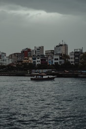 A small boat navigating calm, flooded streets in an urban area during heavy rains.