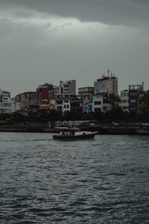A small boat navigating calm, flooded streets in an urban area during heavy rains.