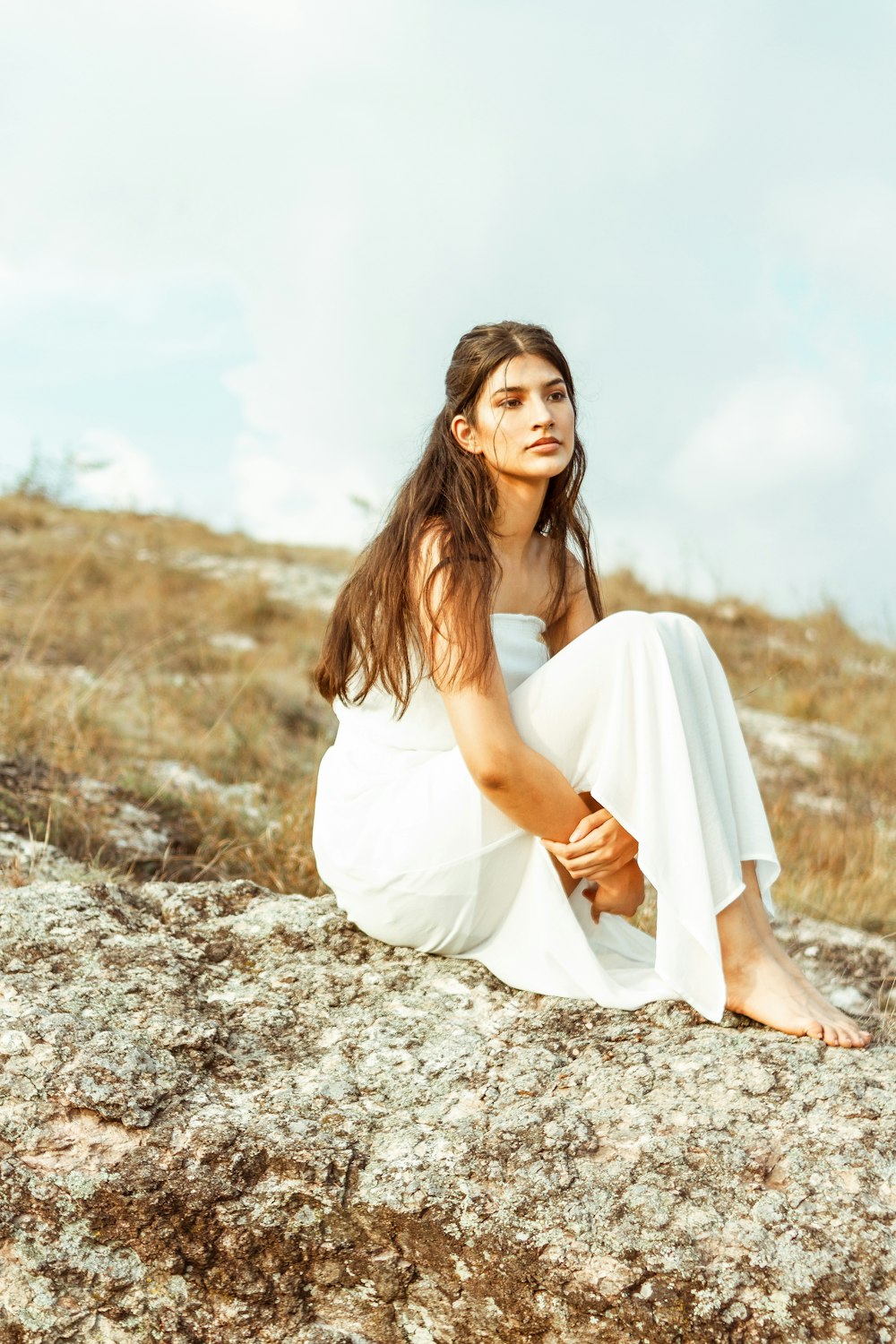 woman in white dress sitting on ground during daytime