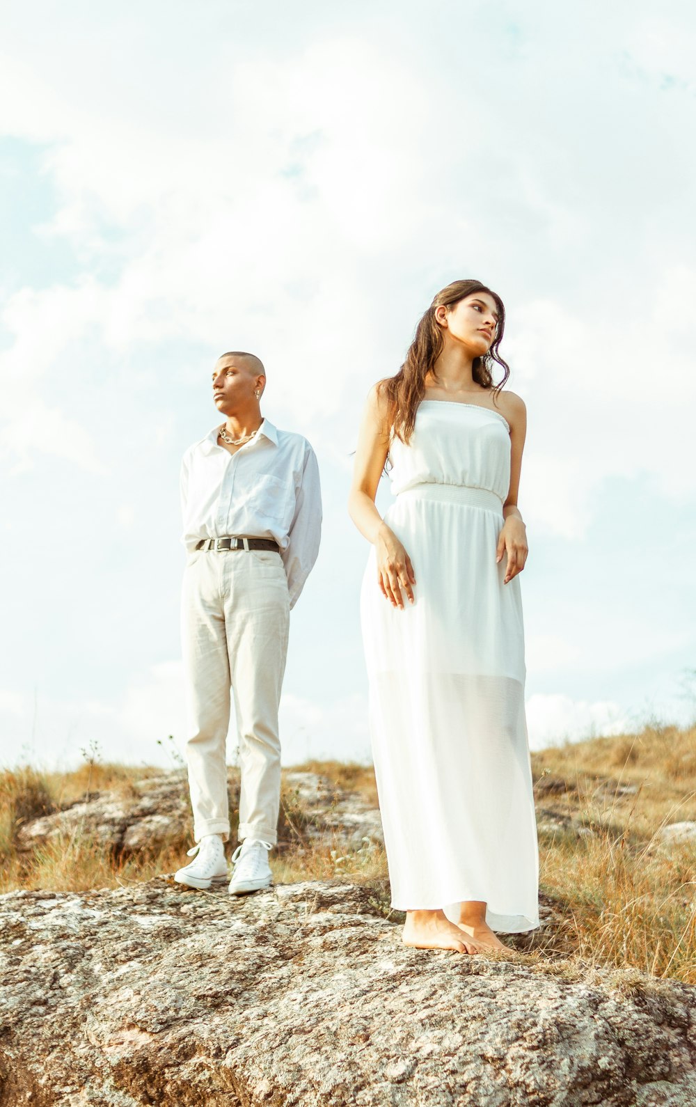 man in white dress shirt and woman in white dress standing on brown grass field during