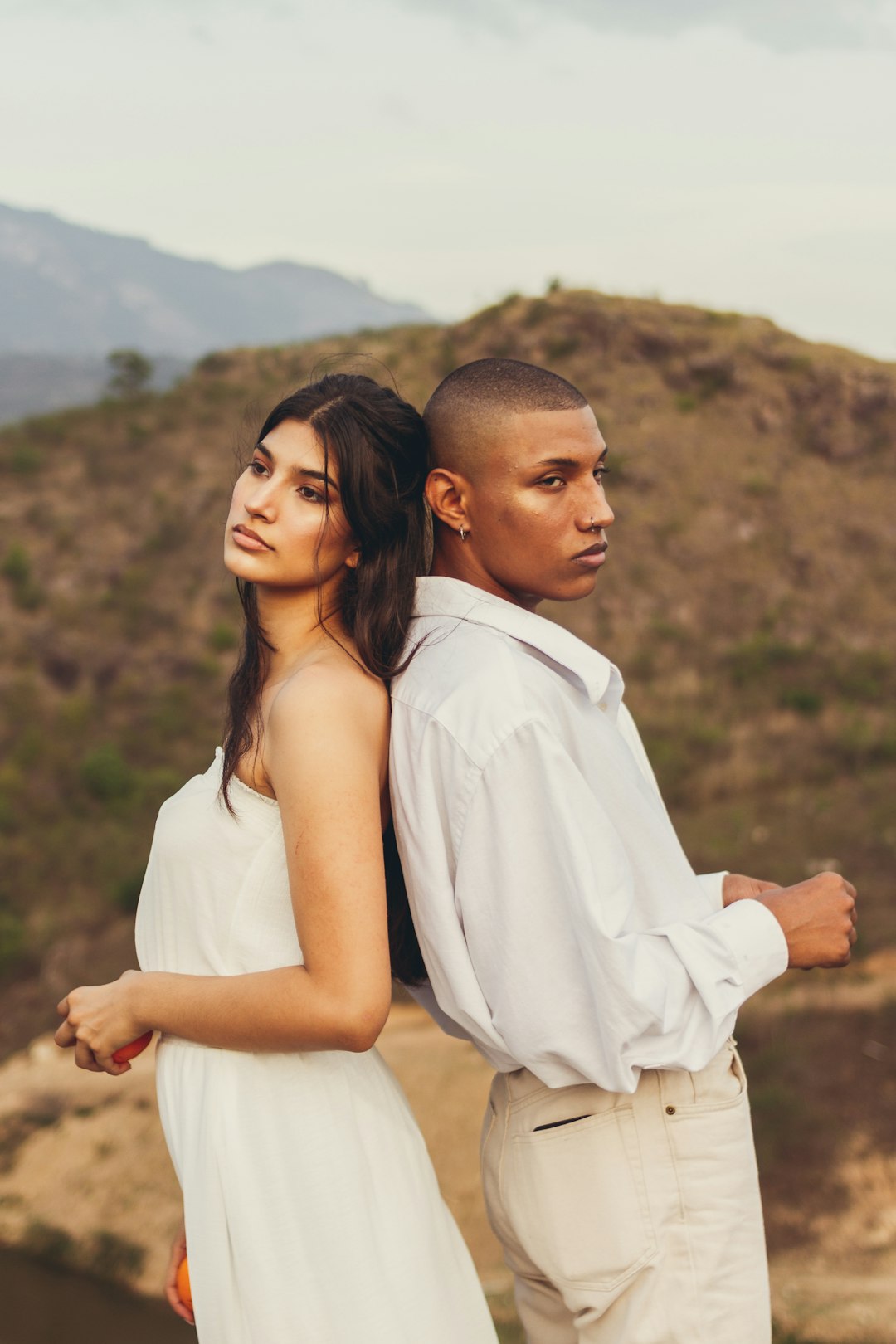 man in white dress shirt holding woman in white sleeveless dress