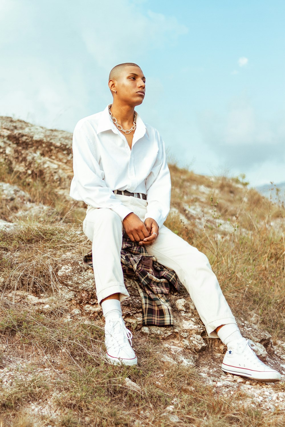 man in white dress shirt and brown pants sitting on brown grass during daytime