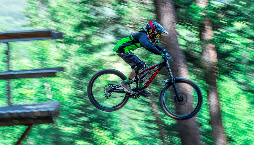 Mann, der tagsüber auf einem schwarzen und orangefarbenen Mountainbike im Wald fährt