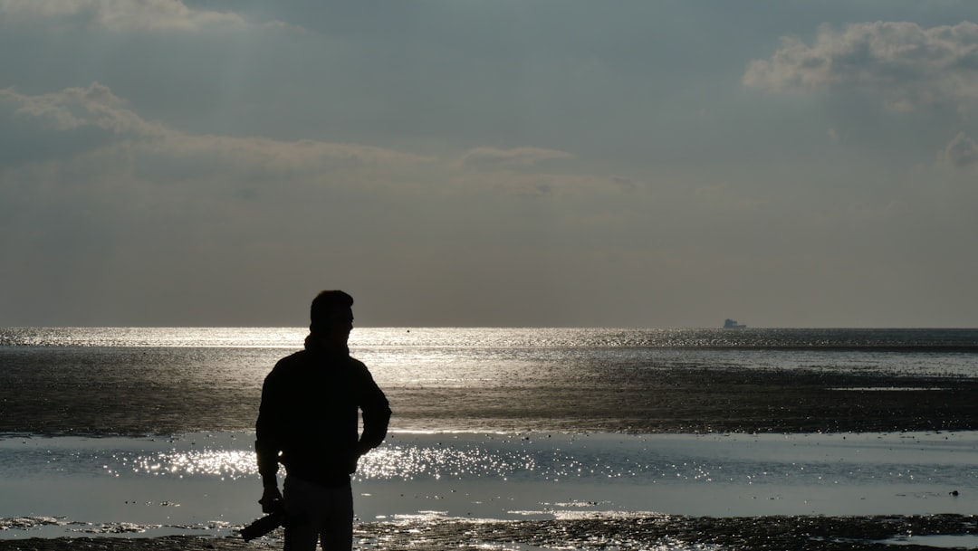 man in black jacket standing on seashore during daytime