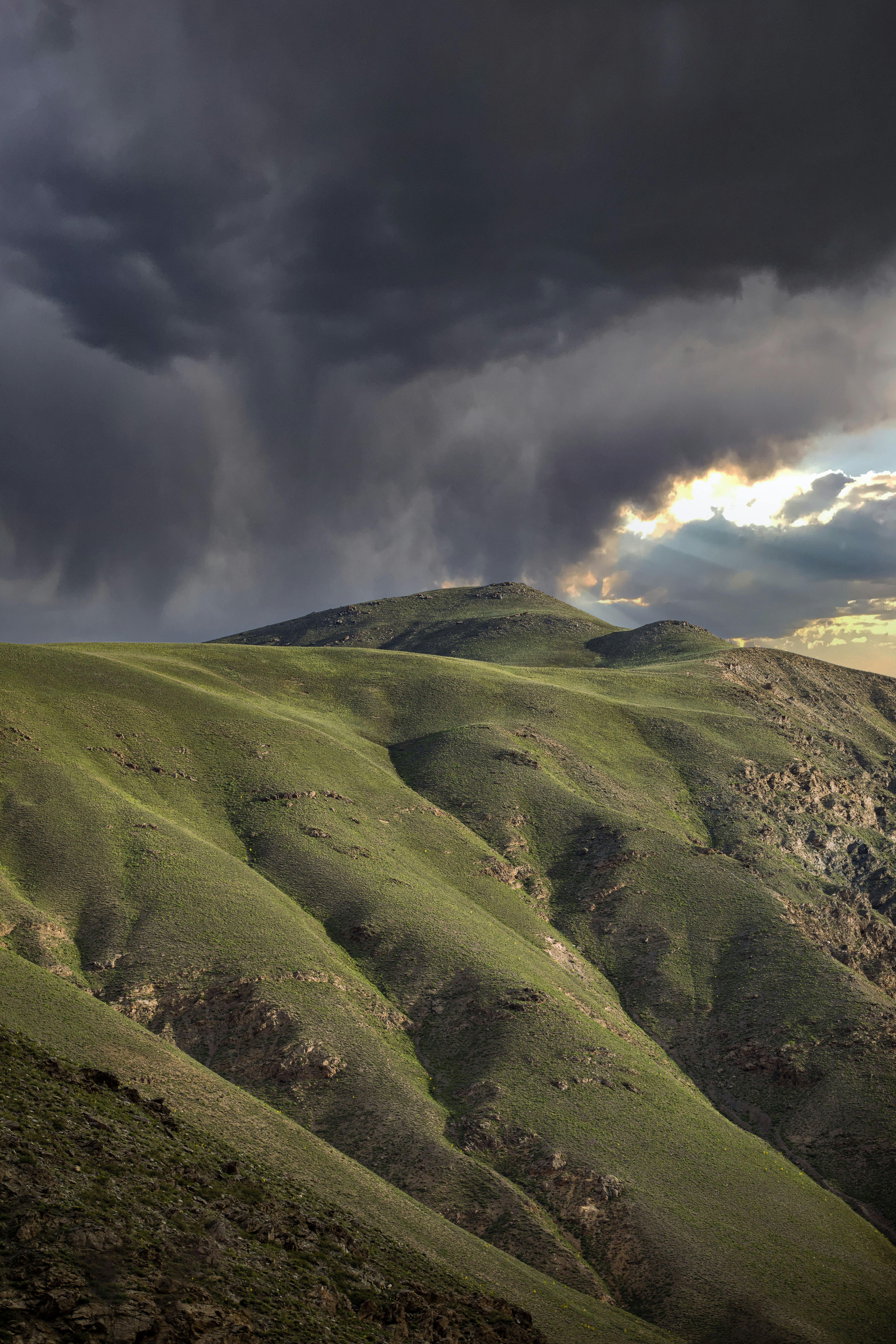 green grass covered mountain under cloudy sky during daytime