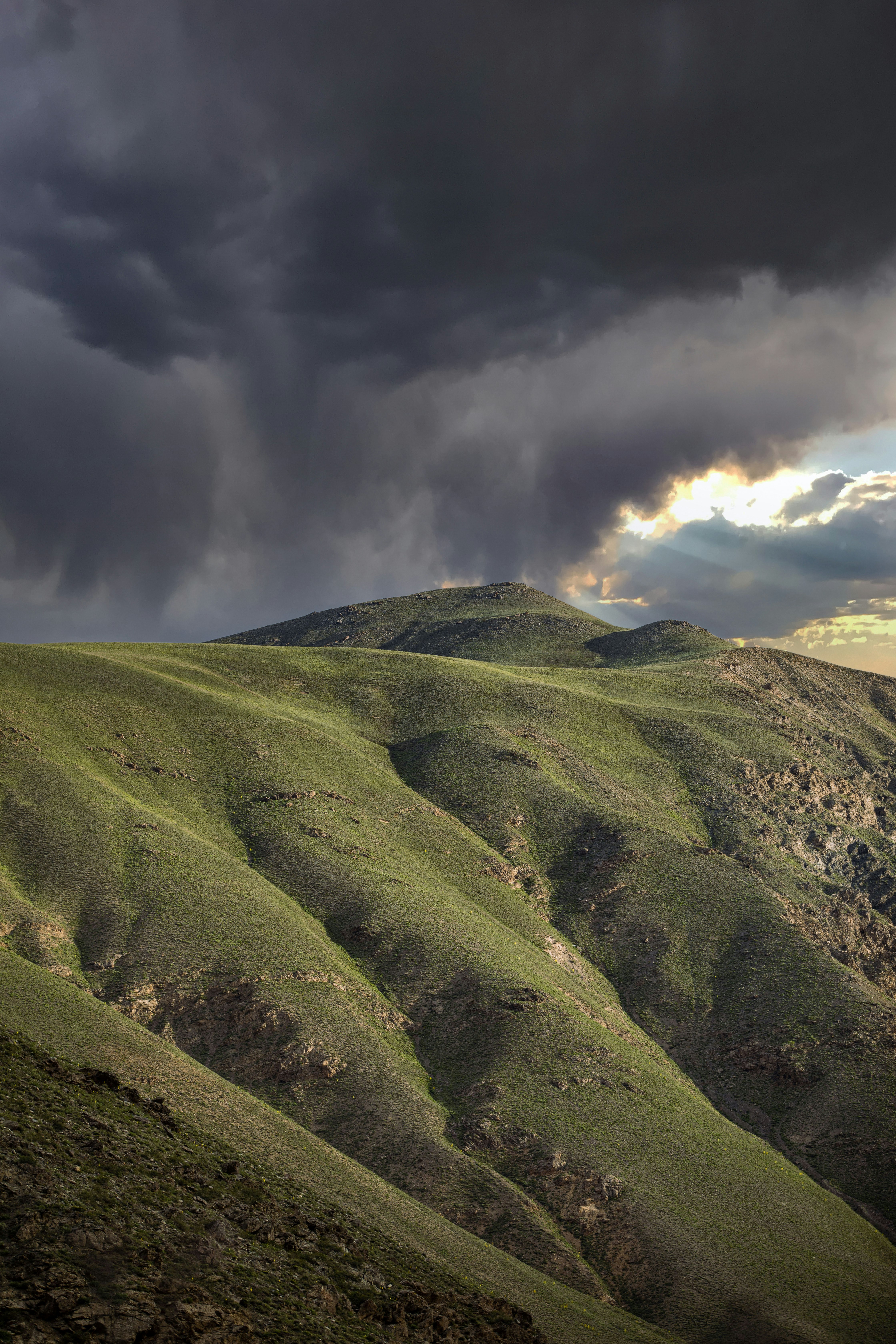 green grass covered mountain under cloudy sky during daytime