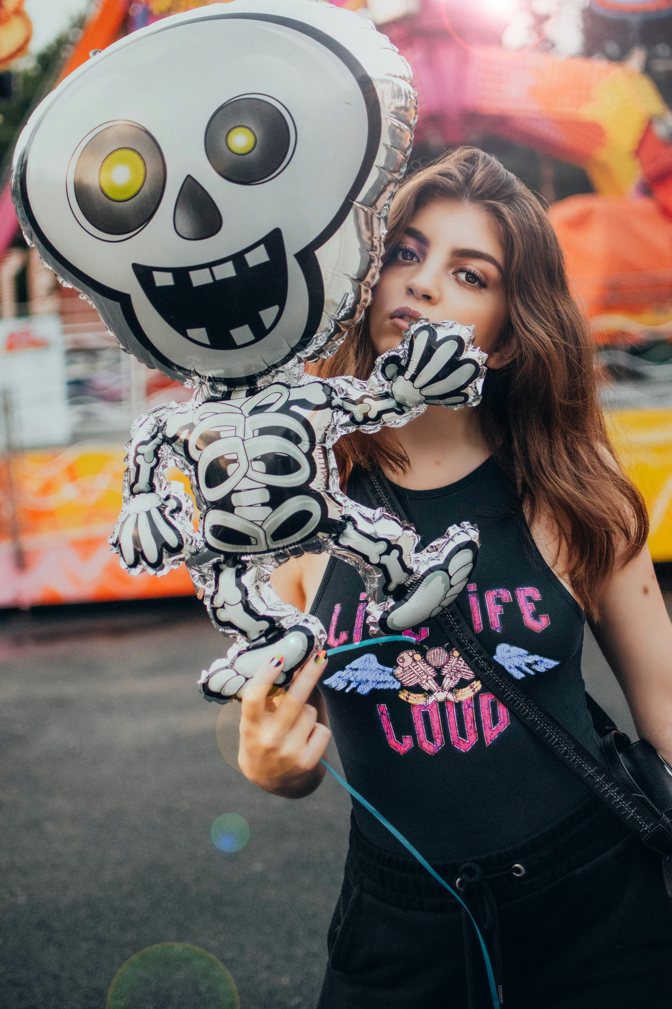 woman in black tank top holding white and black skull print balloon
