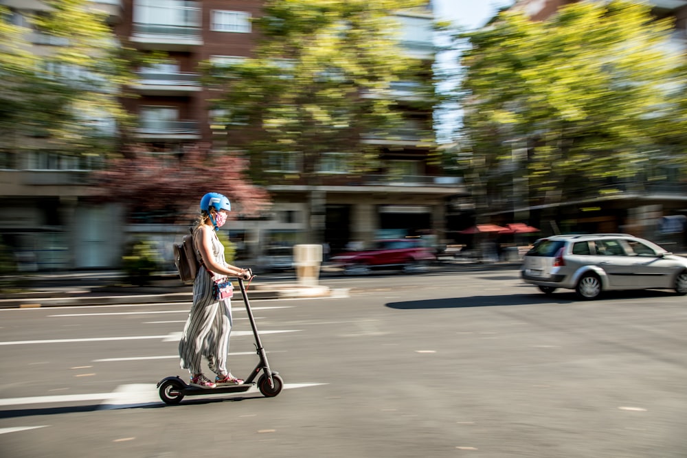 girl in pink dress riding kick scooter on road during daytime