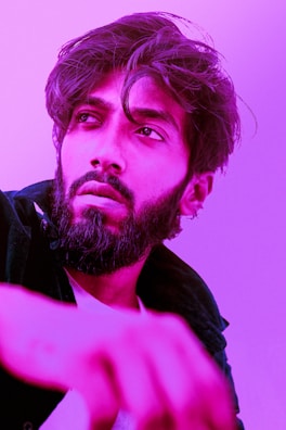 Young man looking thoughtfully at his reflection, noticing beard gaps