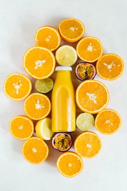 Close-up of vibrant red and yellow detox juices in glass bottles surrounded by fresh citrus fruits