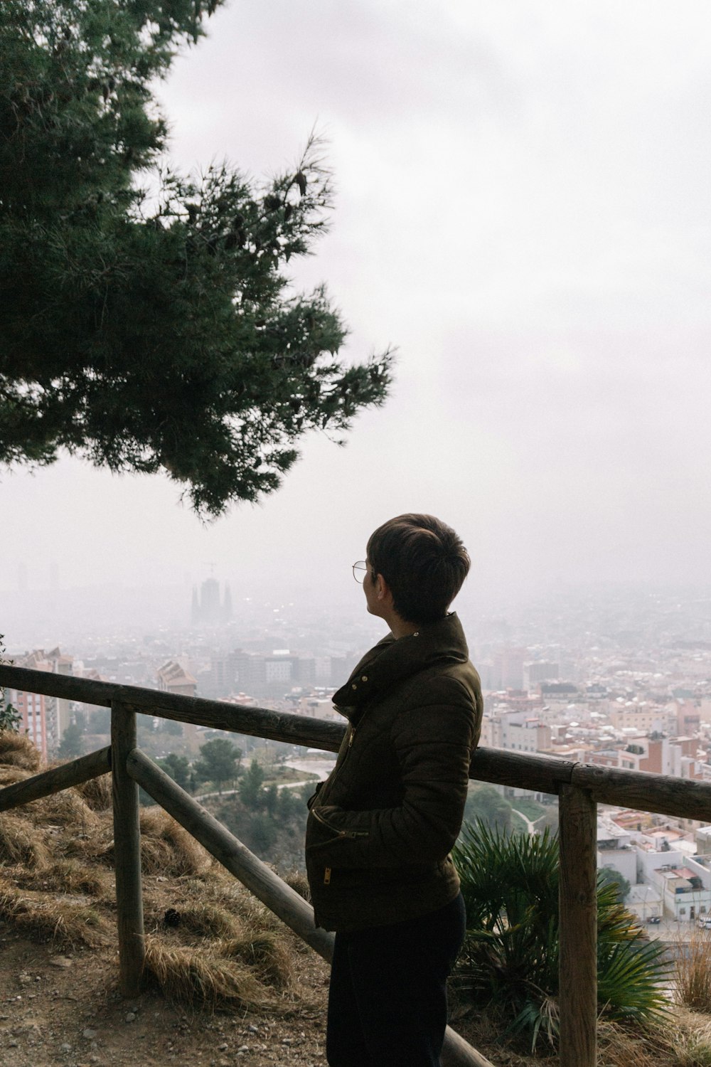 man in brown jacket standing on top of a building looking at the sea during daytime