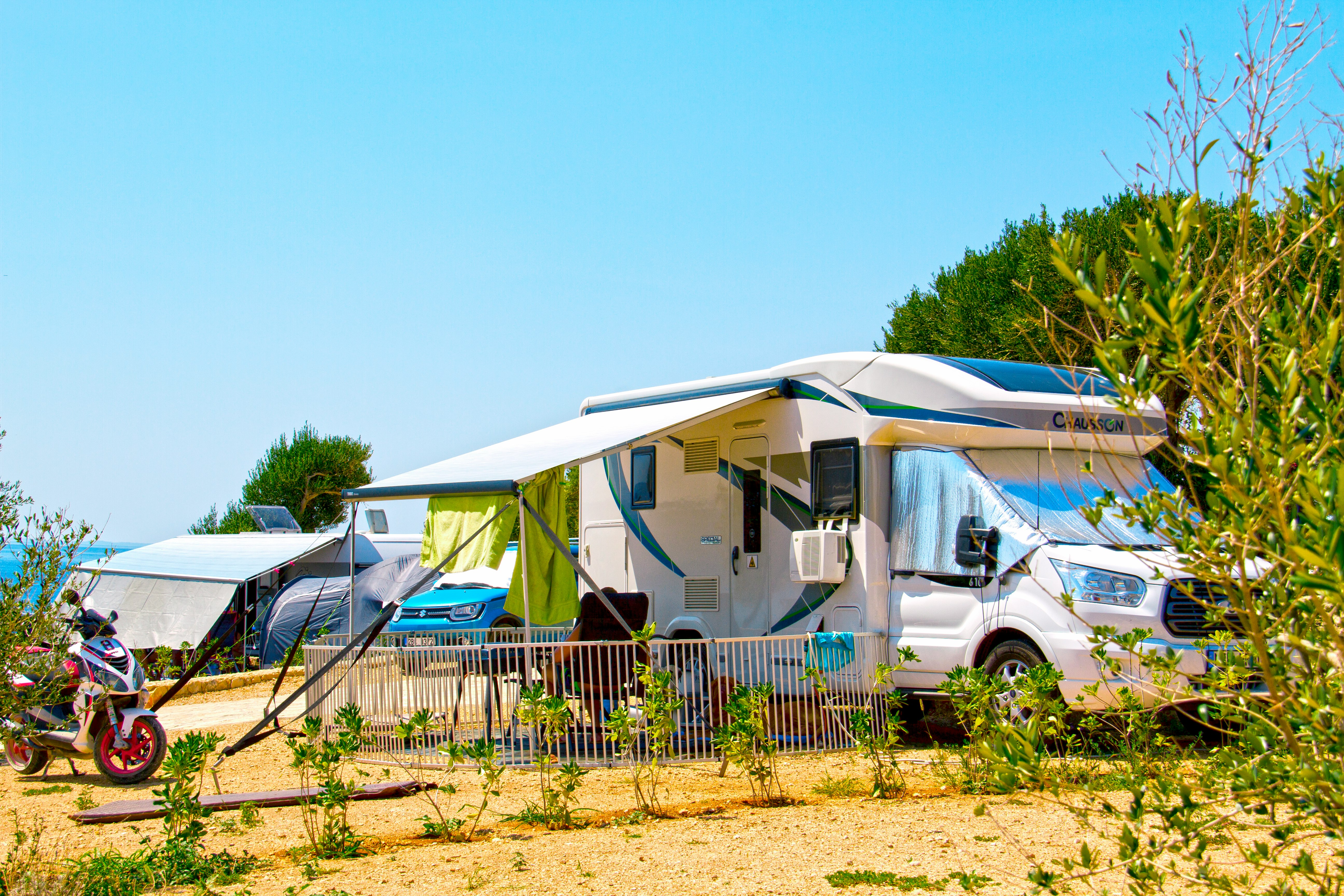 white and blue camper trailer on green grass field during daytime