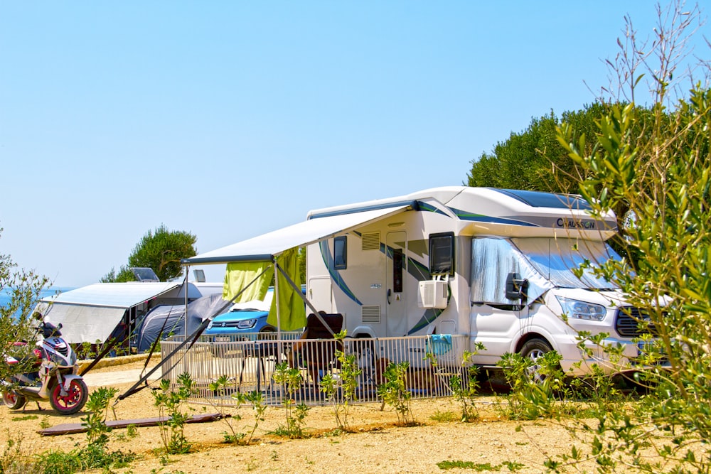 white and blue camper trailer on green grass field during daytime