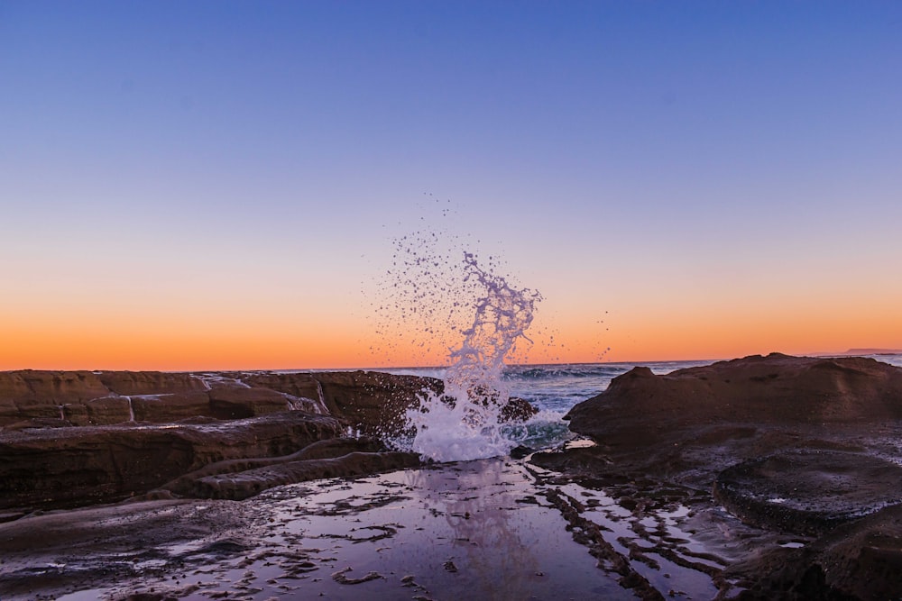 Wasserspritzer am felsigen Ufer während des Sonnenuntergangs