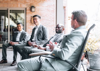 man in gray suit jacket sitting on chair beside man in gray suit jacket