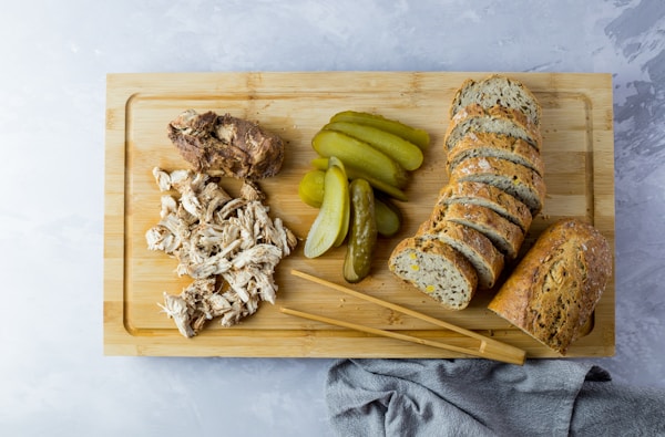 Sliced bread with sliced cucumber and garlic on brown wooden chopping board
