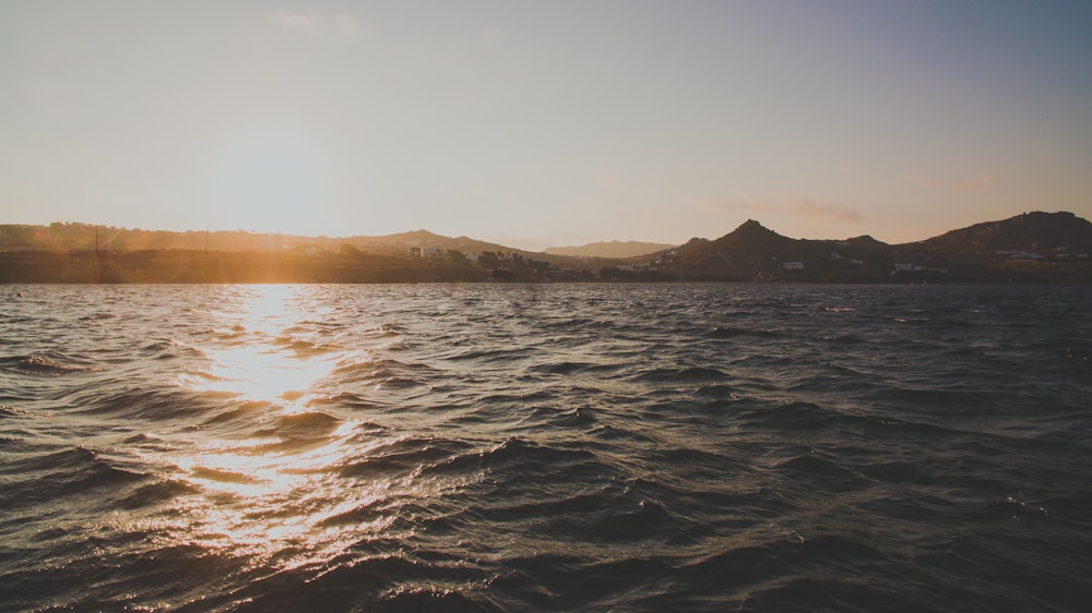 body of water near mountain during daytime