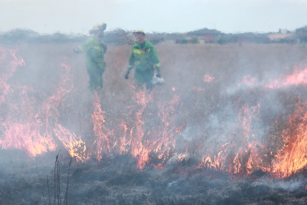 man in green jacket standing on brown soil with green and red smoke