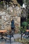 Vintage wrought-iron garden chairs arranged around a marble table under a pergola.