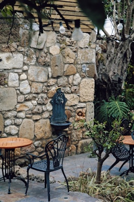 An elegant dining patio styled with water-resistant pillows on classic wrought iron chairs under subtle string lights.
