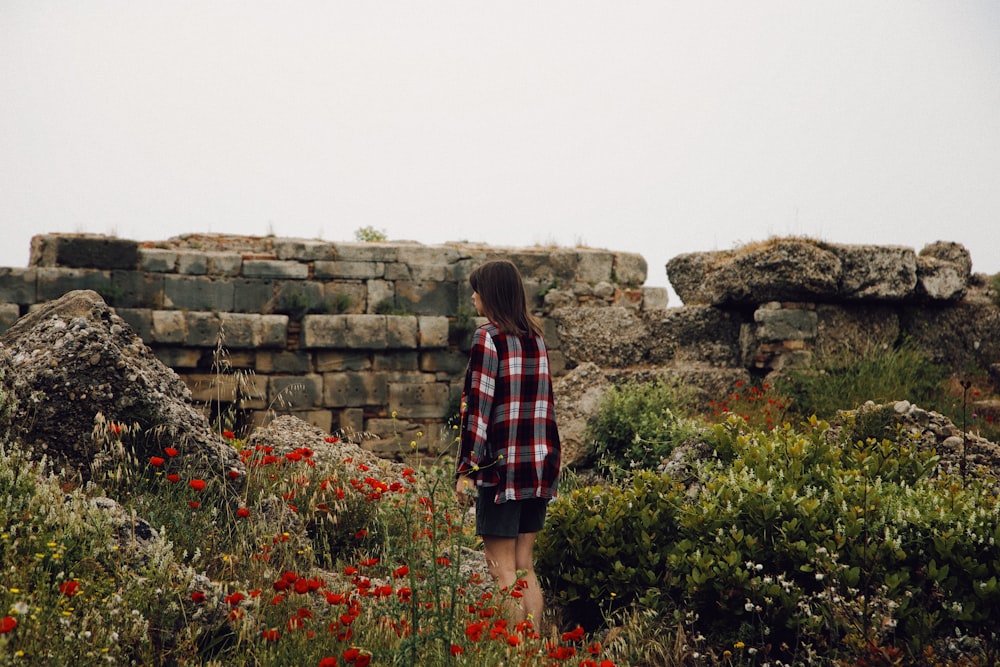 woman in red and black plaid dress shirt standing on green grass field during daytime