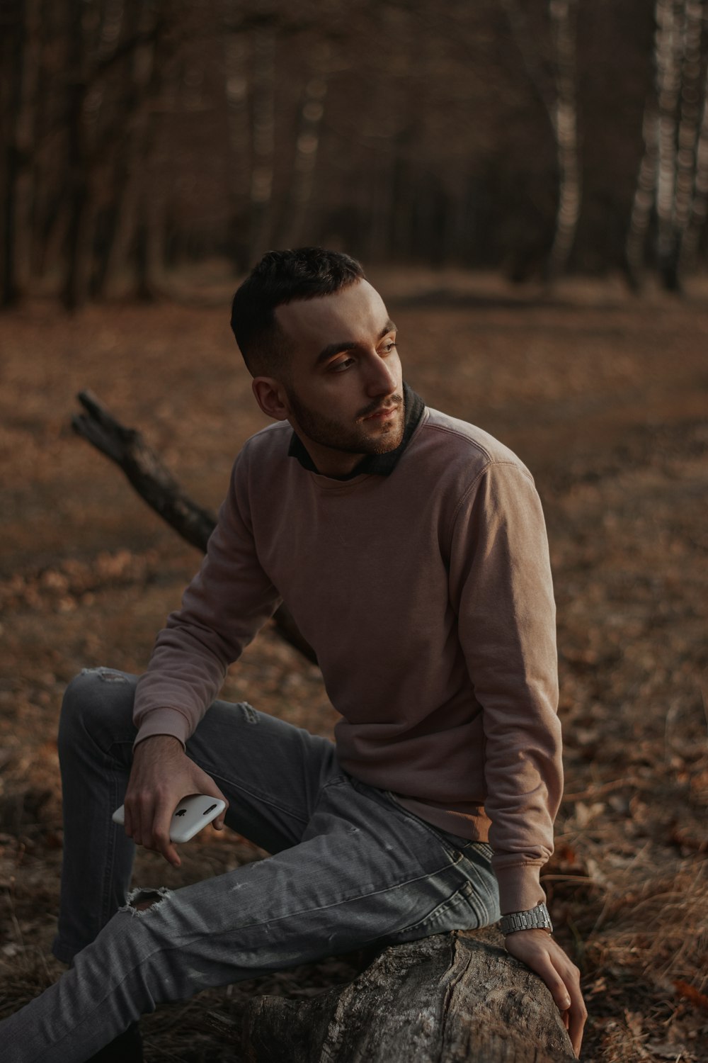 man in brown long sleeve shirt and blue denim jeans sitting on brown dried leaves during