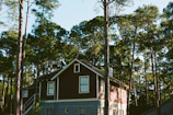 A serene villa nestled among tall pine trees with warm evening lights glowing.