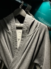 Cozy gray hoodie hanging on a rustic wooden hanger against a soft background