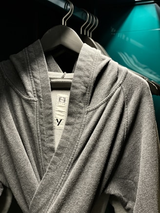 A cozy oversized hoodie in soft gray fabric displayed on a wooden hanger against a warm background.