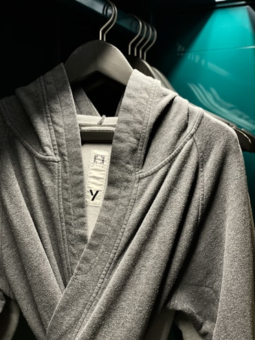 A cozy oversized hoodie in soft gray fabric displayed on a wooden hanger against a warm background.