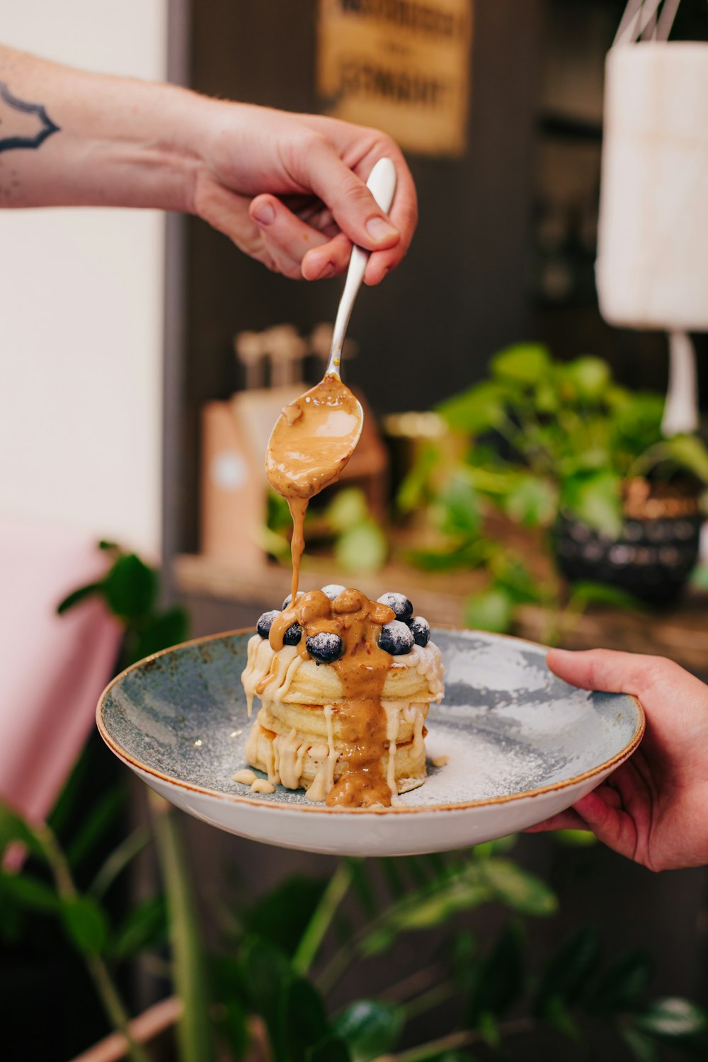 person pouring cream on brown and white ice cream on stainless steel bowl