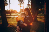 A veteran smiling warmly while holding hands with a child in a sunlit park.