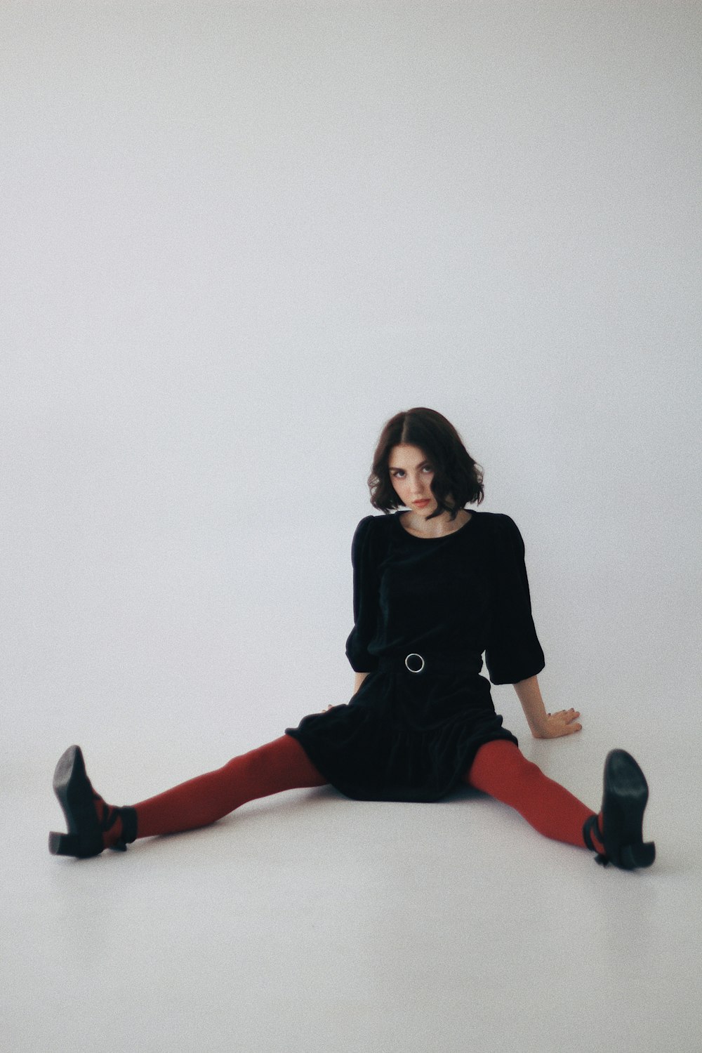 woman in black long sleeve shirt and red pants sitting on white floor