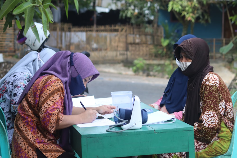 woman in brown and red hijab sitting on green box