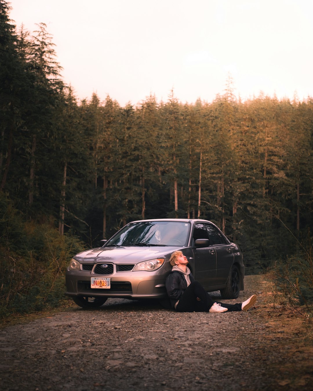 woman in black jacket sitting on gray car hood during daytime