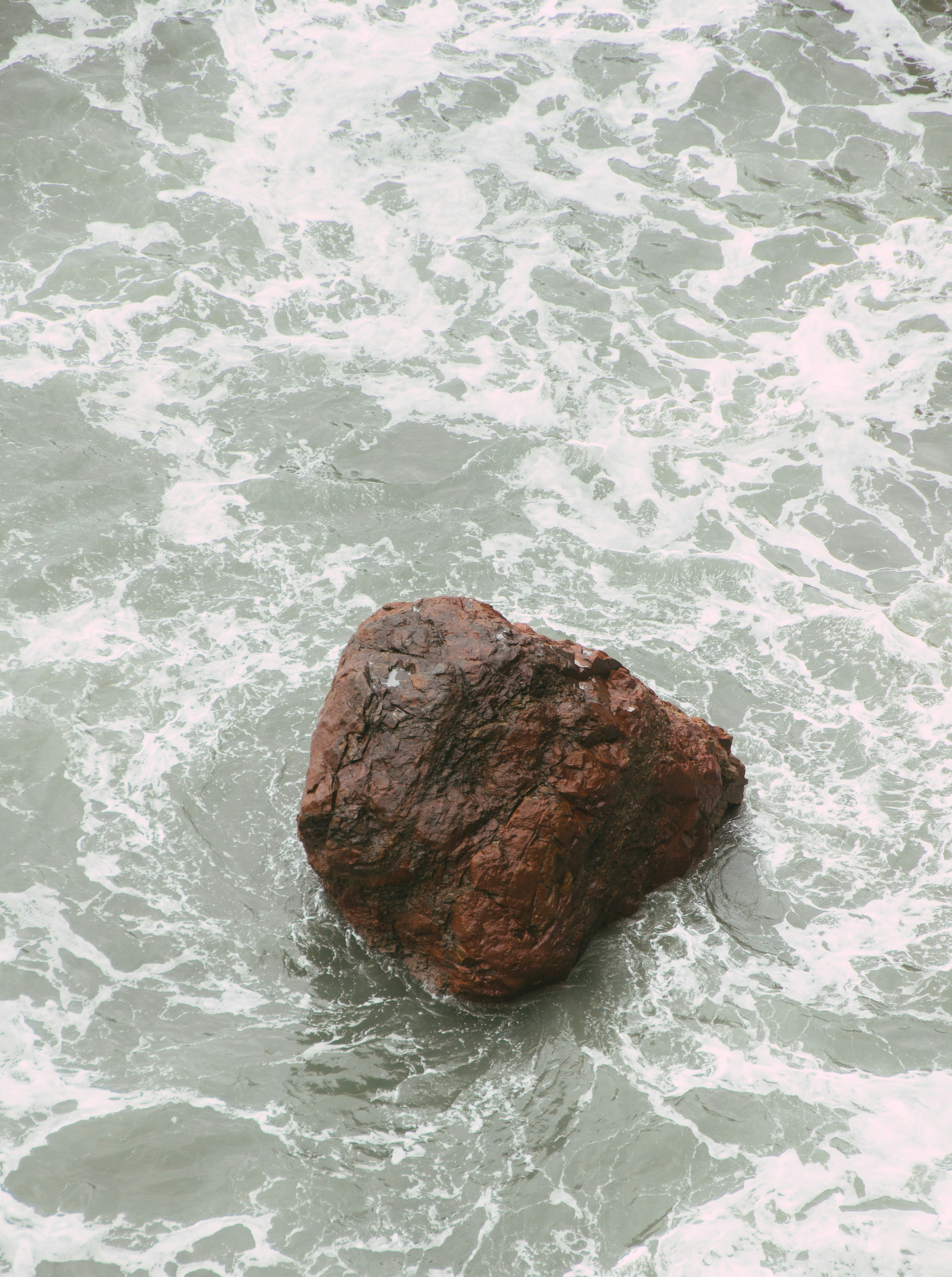 brown rock on body of water