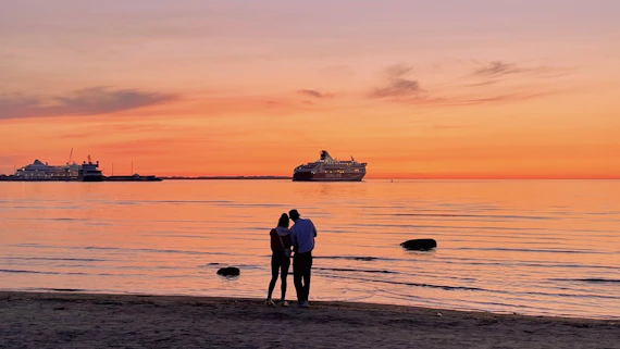silhouette of 2 people standing on beach during sunset