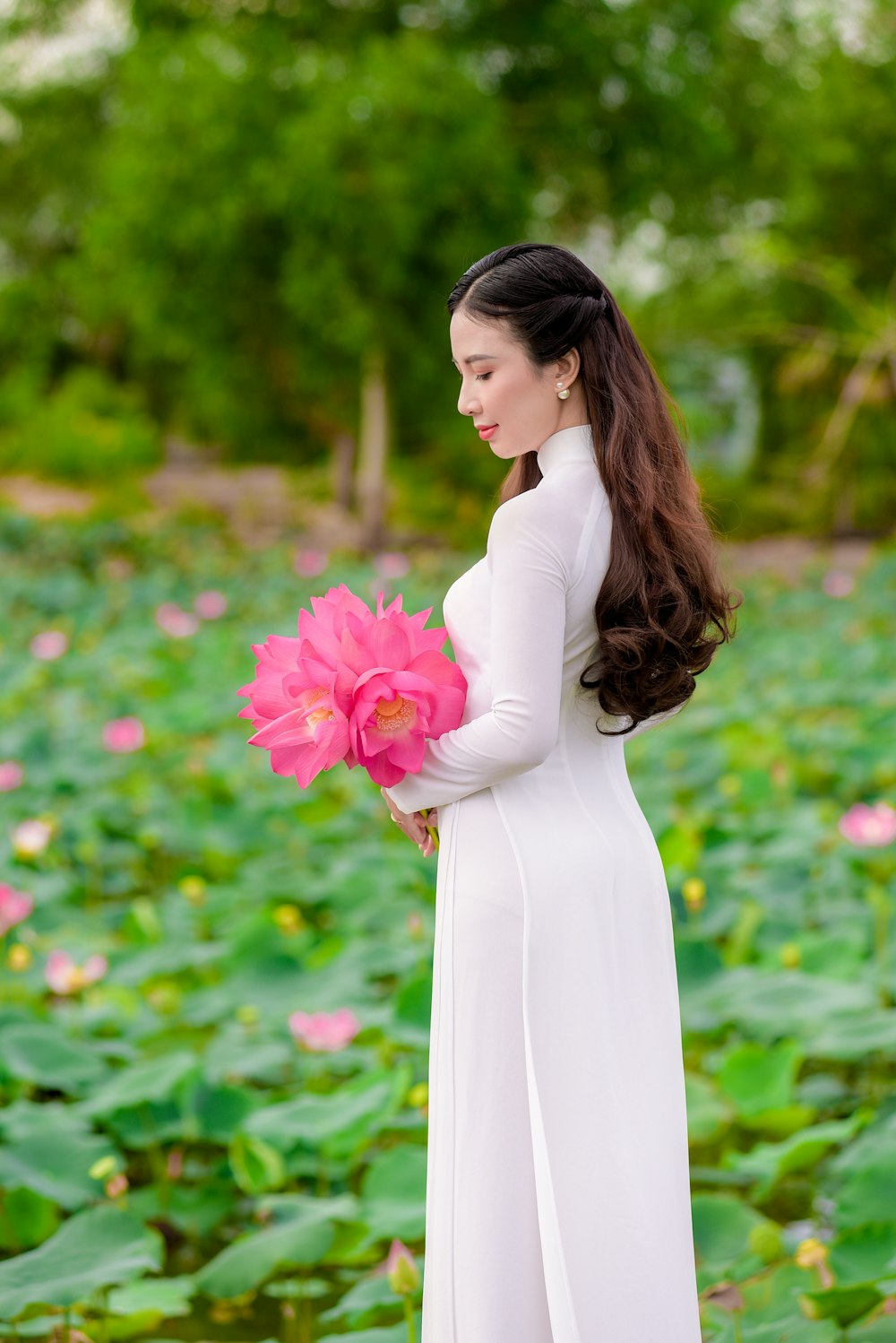 woman in white dress holding pink flower bouquet