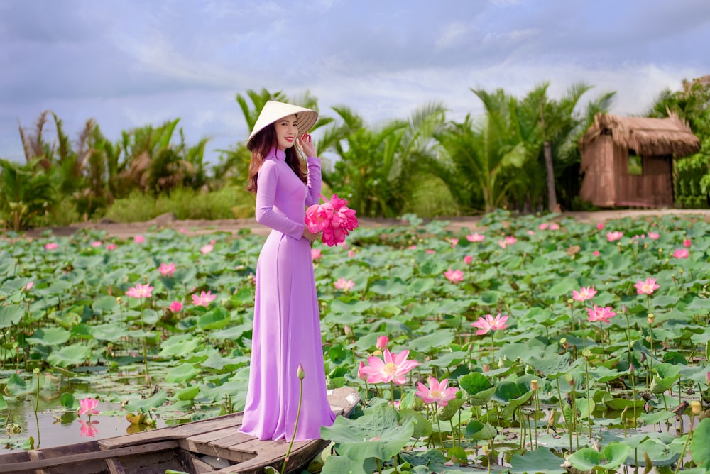 woman in purple dress standing on flower field during daytime