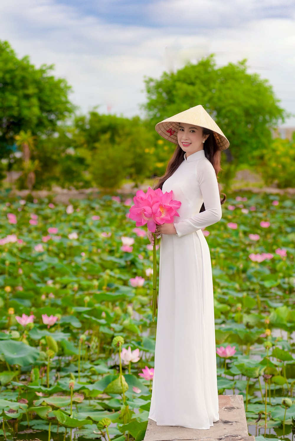 woman in white long sleeve dress standing on flower field during daytime