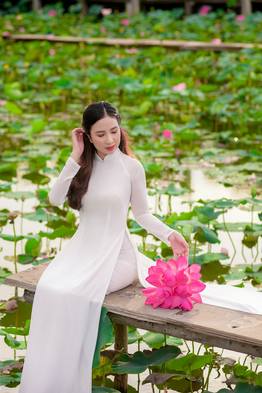 woman in white long sleeve dress sitting on brown wooden bench