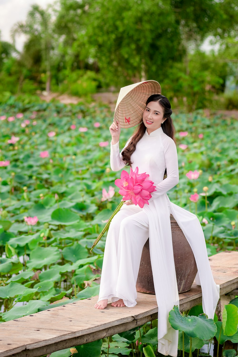 woman in white dress wearing brown straw hat standing on green grass field during daytime