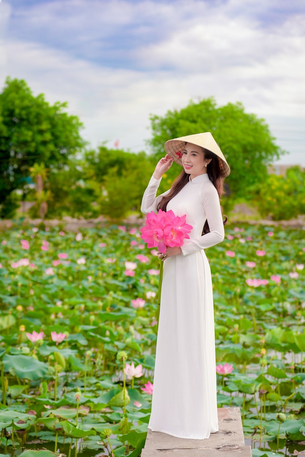 woman in white dress standing on flower field during daytime